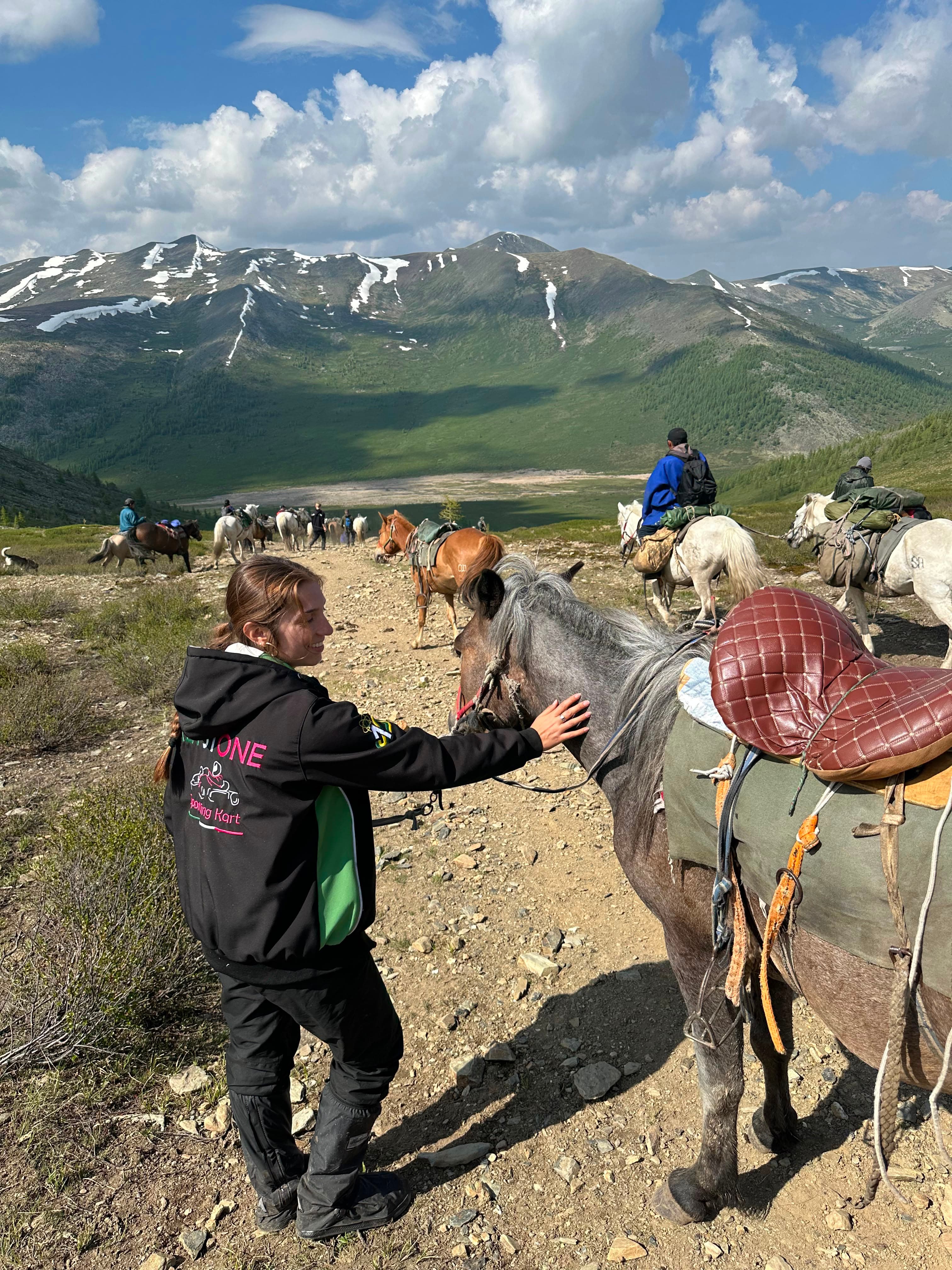 Sofia greeting a horse on a mountain trail during the Mongolia trek